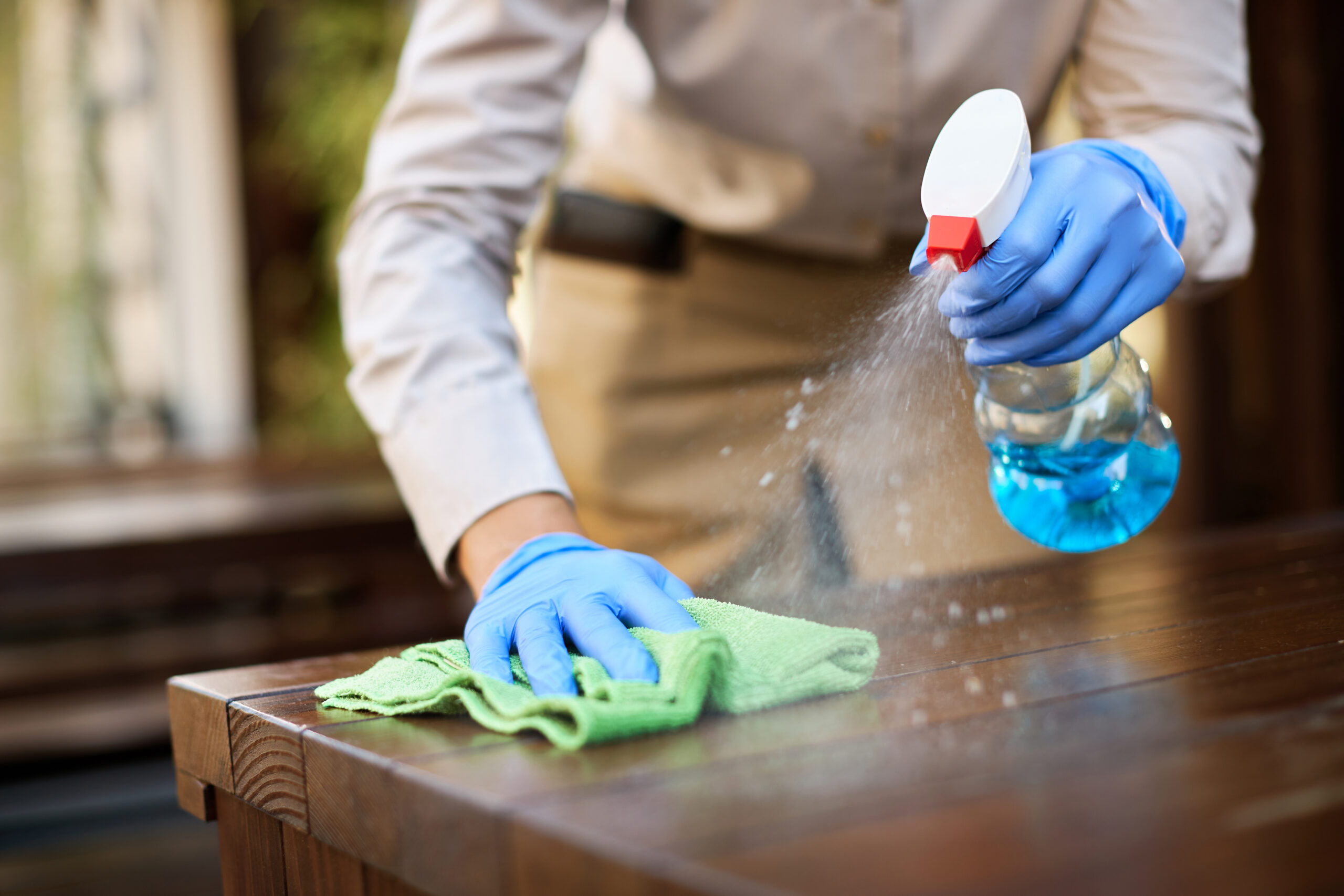 Close-up of waitress cleaning tables with disinfectant due to coronavirus epidemic.